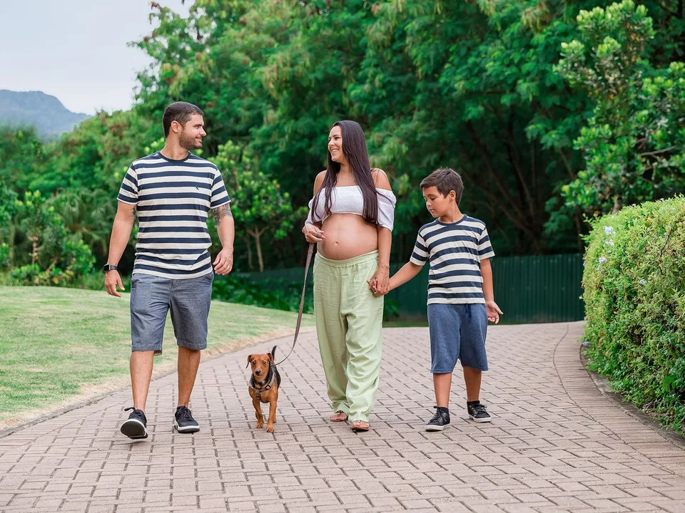 Un couple et leur fils promènent un petit chien en laisse sur une allée de parc